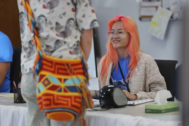 Elections staff assist early voters line up at the City of Minneapolis early voting center, Friday, September 20, 2024, in Minneapolis, Minn. (AP Photo/Adam Bettcher)