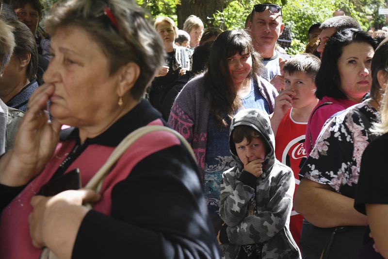 People evacuated from fighting between Russian and Ukrainian forces queue to receive humanitarian aid at a distribution center in Kursk, Russia, Monday, Aug. 12, 2024. (AP Photo)