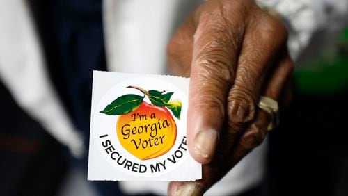 A poll worker holds a Georgia voter sticker ready to be handed to a voter at Berean Christian Church on Oct. 17, 2022. (Miguel Martinez/The Atlanta Journal-Constitution/TNS)