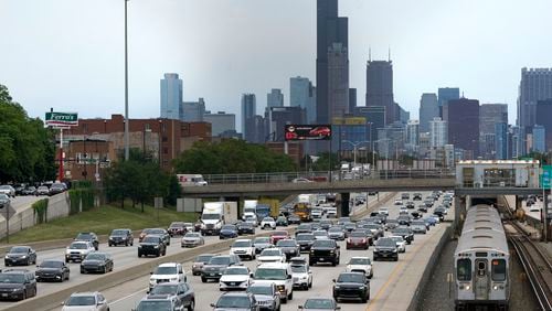 FILE - Motorists head southbound in the local and express lanes on Interstates 90-94 in slow and thickening traffic as a CTA train enters a station on the first day of the Fourth of July holiday weekend, July 1, 2022, in Chicago. Millions of Americans are preparing to get out of town sometime in the coming Fourth of July holiday week, which will likely mean busy roads as well as packed airports and train stations. (AP Photo/Charles Rex Arbogast, File)