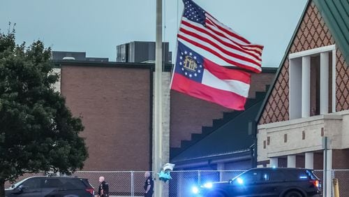 The American and Georgia flags outside Apalachee High School fly at half-staff a day after two students and two teachers were gunned down. Nine others were injured. (John Spink/AJC)