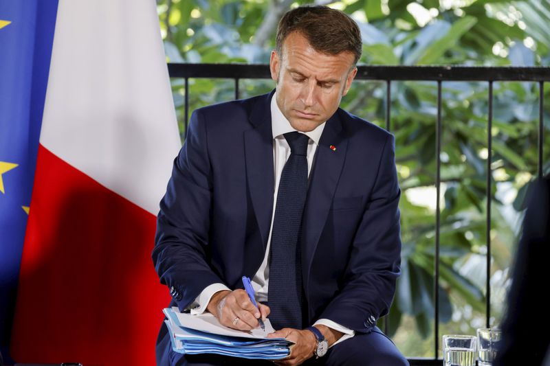 French President Emmanuel Macron takes notes during a meeting with New Caledonia's elected officials and local representatives at the French High Commissioner Louis Le Franc's residence in Noumea, New Caledonia, Thursday, May 23, 2024. Macron has landed in riot-hit New Caledonia, having crossed the globe by plane from Paris in a high-profile show of support for the French Pacific archipelago wracked by deadly unrest and where indigenous people have long sought independence from France. (Ludovic Marin/Pool Photo via AP)