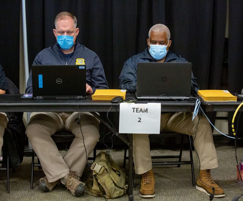 GBI agents Daniel Sims (L) and Robert Justice perform an audit of absentee ballot signatures at the Cobb County Civic Center on Dec. 22, 2020.  STEVE SCHAEFER FOR THE ATLANTA JOURNAL-CONSTITUTION