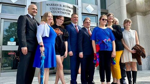 FILE — Two teens challenging New Hampshire's new law banning transgender girls from girls' sports teams, Parker Tirrell, third from left, and Iris Turmelle, sixth from left, pose with their families and attorneys in Concord, N.H., Monday, Aug. 19, 2024, after a judge granted an emergency request to allow one of the girls to play soccer while their lawsuit continues. (AP Photo/Holly Ramer, File)