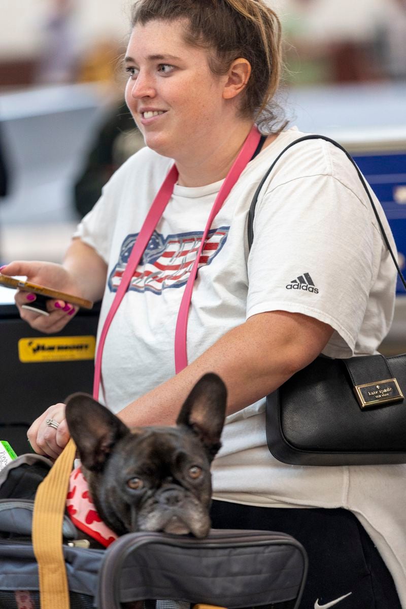  Ricky Jimenez and her dog Murphy wait in the ticket counter line Saturday at Hartsfield-Jackson Atlanta International Airport after hundreds of airline flights were canceled due to a global technology outage Friday.    (Steve Schaefer / AJC)