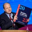 Colorado Gov. Jared Polis holds up a copy of Project 2025 as he speaks during the Democratic National Convention on Aug. 21, 2024, in Chicago. (J. Scott Applewhite/AP)