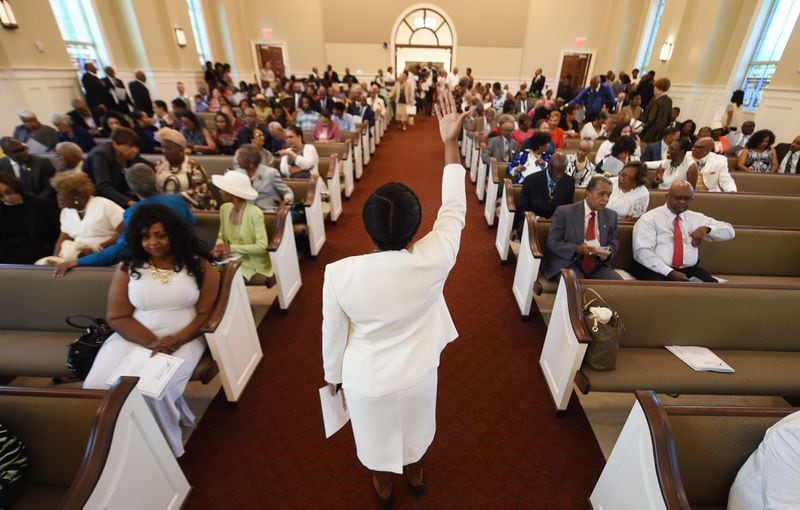 Usher Jazmine Frear directs parishioners to their seats as members attend the first morning worship service. KENT D. JOHNSON / AJC