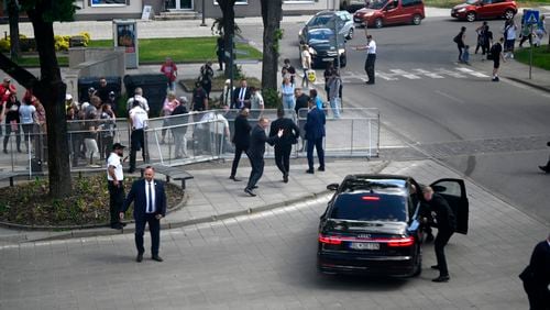 FILE - Bodyguards take Slovak Prime Minister Robert Fico in a car from the scene after he was shot and injured following the cabinet's away-from-home session in the town of Handlova, Slovakia, on May 15, 2024. Slovakia’s authorities started to investigate a suspect in an attempted assassination on populist Prime Minister Robert Fico as a terror attack, the country’s prosecutor general said on Thursday, July 4, 2024. (Radovan Stoklasa/TASR via AP)