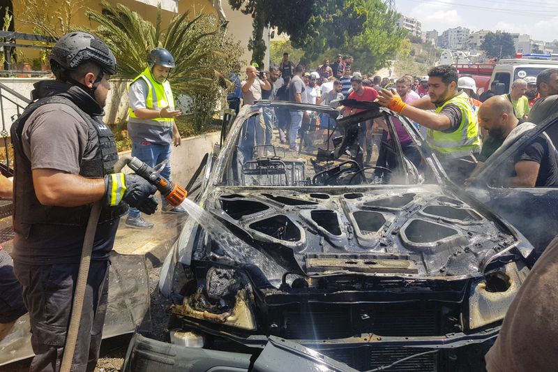 Civil Defense workers inspect the remains of a burned car that was hit by an Israeli strike in the southern port city of Sidon, Lebanon, Monday, Aug. 26, 2024. (AP Photo/Mohammed Zaatari)