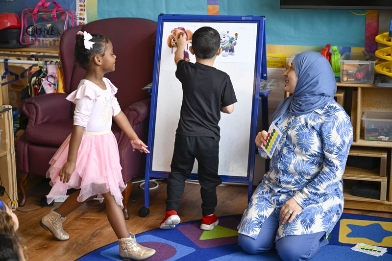 Preschool teacher Tinhinane Meziane, right, watches her students vote the most popular character of the TV show PAW Patrol at the ACCA Child Development Center, Thursday, Sept. 19, 2024, in Annandale, Va. The students are getting foundational lessons on how to live in a democracy by allowing them to regularly vote on different things through out the day. (AP Photo/John McDonnell)