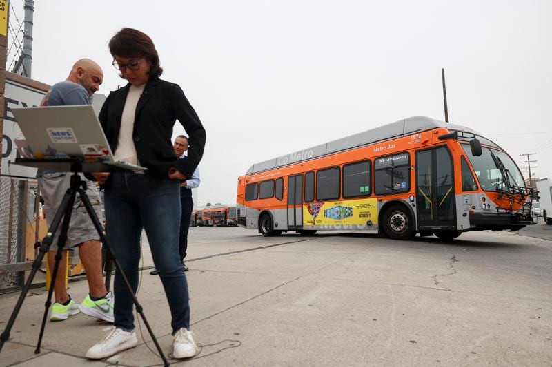 A bus passes by news media in front of a Los Angeles MTA bus depot near the site where an overnight a bus was hijacked by an armed suspect with passengers on board Wednesday, Sept. 25, 2024, in Los Angeles. (AP Photo/Ryan Sun)