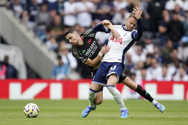 Tottenham's James Maddison is pulled back by Arsenal's Jorginho during the English Premier League soccer match between Tottenham Hotspur and Arsenal in London, Sunday, Sept. 15, 2024. (AP Photo/Kin Cheung)