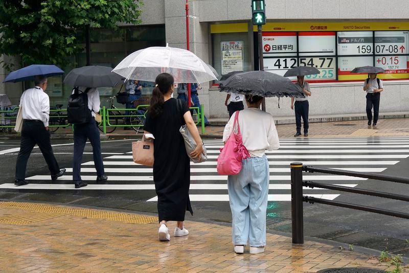 People walk in front of an electronic stock board showing Japan's Nikkei index at a securities firm Friday, July 12, 2024, in Tokyo. (AP Photo/Eugene Hoshiko)