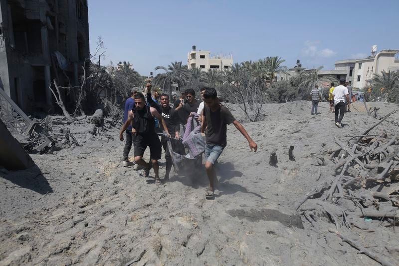 Palestinians evacuate a dead person from a site hit by an Israeli bombardment on Khan Younis, southern Gaza Strip, Saturday, July 13, 2024. Israel said it targeted Hamas’ shadowy military commander in a massive strike Saturday in the crowded southern Gaza Strip that killed at least 71 people, according to local health officials. Hamas immediately rejected the claim that Mohammed Deif was in the area. (AP Photo/Jehad Alshrafi)