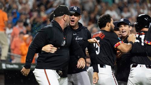 New York Yankees manager Aaron Boone, second from left, and Baltimore Orioles major league field coordinator/catching instructor Tim Cossins, left, argue after players cleared the benches during the ninth inning of a baseball game, Friday, July 12, 2024, in Baltimore. (AP Photo/Stephanie Scarbrough)