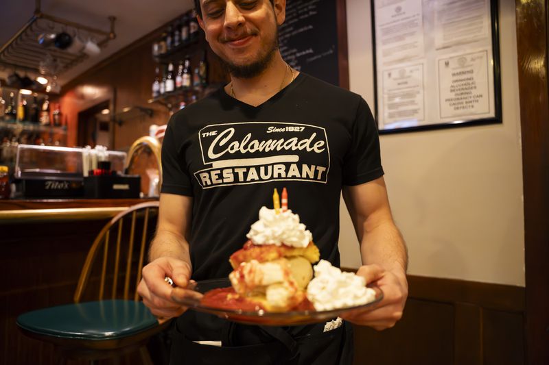 A server at the Colonnade delivers a towering plate of strawberry shortcake.