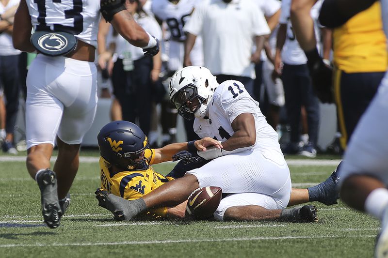 West Virginia quarterback Garrett Greene fumbles as he is defended by Penn State defensive end Abdul Carter (11) during the first half of an NCAA college football game in Morgantown, W.Va., Saturday, Aug. 31, 2024. (AP Photo/Kathleen Batten)