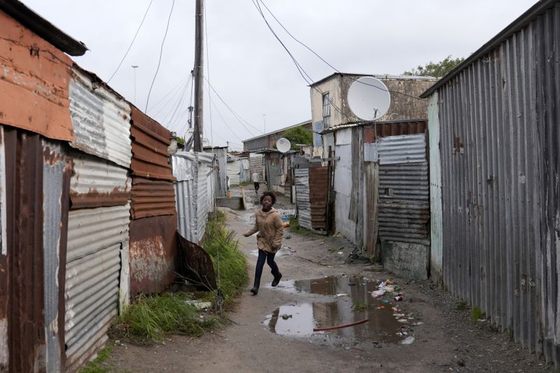 A child makes their way through drenched passages in Khayelitsha, Cape Town, South Africa, Thursday July 11, 2024. The South African city of Cape Town and surrounding areas have been hit by more storms, ripping roofs off houses and causing widespread flooding. (AP Photo/Nardus Engelbrecht)