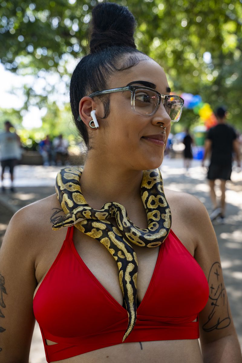 Kendra Hill walks around at the Pure Heat Community Festival in Piedmont Park with her pet snake on Sunday, Sept. 1, 2024.  