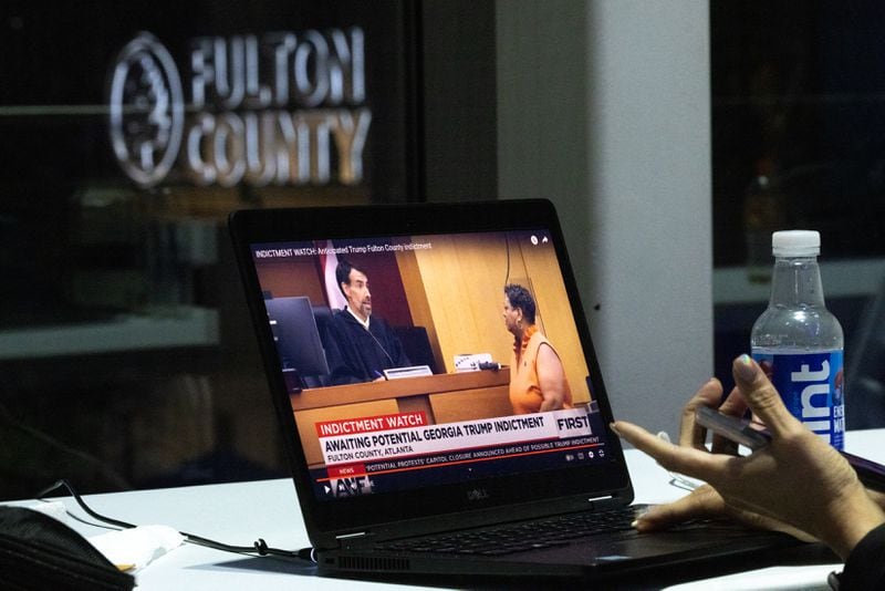A reporter in Fulton County Government Center watches Judge Robert McBurney on a laptop as an indictment in an election interference case against Donald Trump and his supporters is handed up in Atlanta on Monday, August 14, 2023. (Arvin Temkar / arvin.temkar@ajc.com)