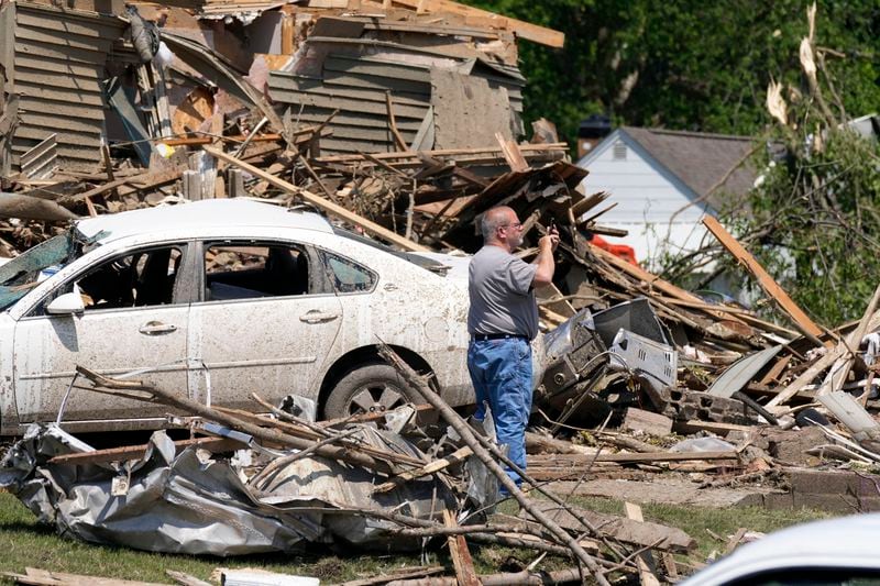 A man takes a photo in front of a tornado damaged home, Wednesday, May 22, 2024, in Greenfield, Iowa. (AP Photo/Charlie Neibergall)
