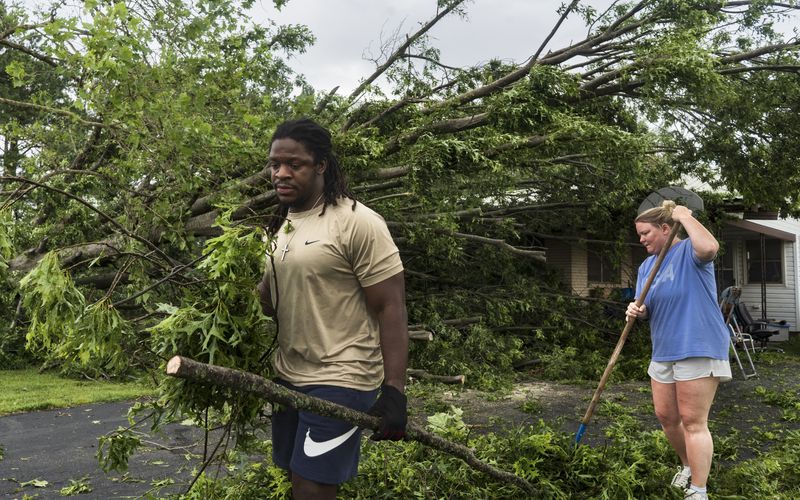 Will Worthey, left, and Lindsey Worthey of Rogers ,help clear debris from a downed tree at the home of Betty Wood on South 24th Street Sunday, May 26, 2024, in Rogers, Ark. Powerful storms left a wide trail of destruction across Texas, Oklahoma and Arkansas. (Charlie Kaijo/The Northwest Arkansas Democrat-Gazette via AP)