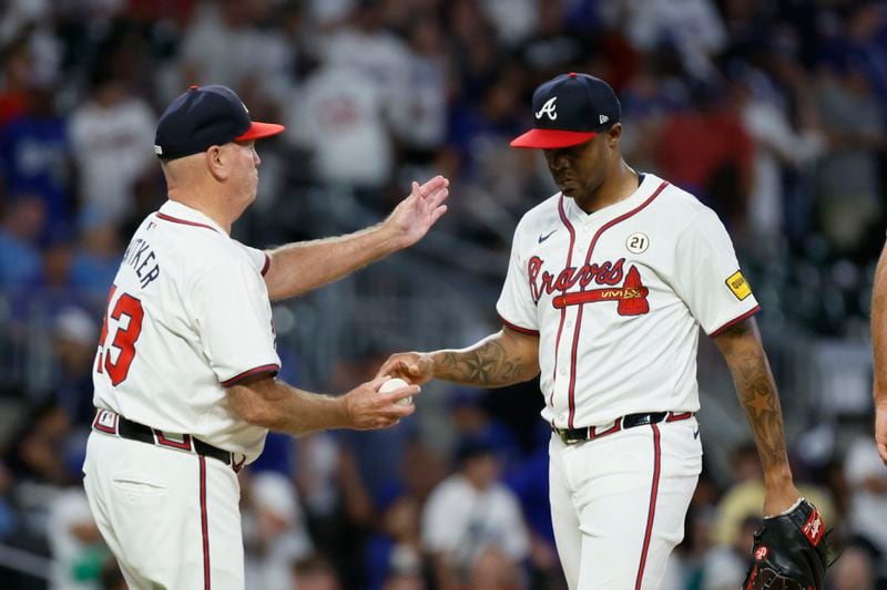 Raisel Iglesias (right) hands the ball to manager Brian Snitker after a rough ninth-inning outing.