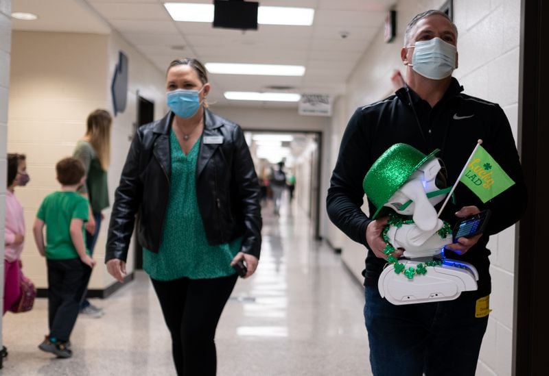 Lisa and Chris Kocks, founders of RoboSolucio, carry Ai Puppy, their robotic teacher assistant, to a third-grade classroom at Rock Springs Elementary School in Gwinnett County on Wednesday afternoon, March 17, 2021. Ben Gray for the Atlanta Journal-Constitution