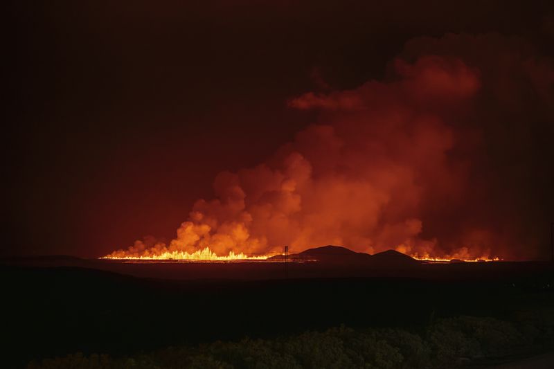 A new volcanic eruption is seen from the intersection between Reykjanesbraut, Iceland, and the road to Grindavik, Thursday, Aug. 22, 2024. (AP Photo/Marco di Marco)