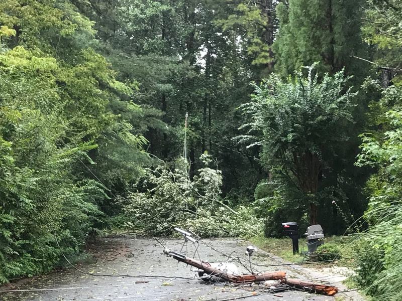 Two downed trees and a broken utility pole lie in the road on Village Court in Snellville on Tuesday morning.