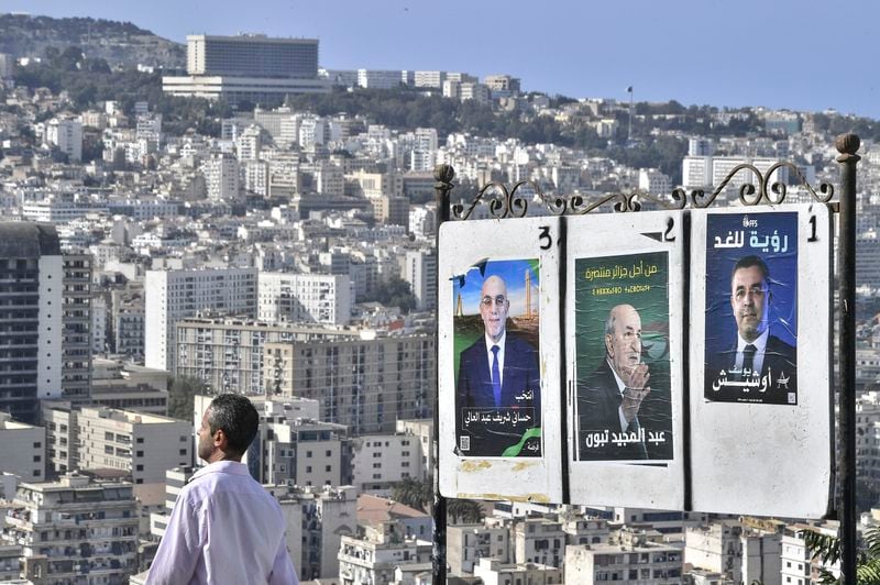 A man walks past electoral banners of presidential candidate, including President Abdelmadjid Tebboune, center, Tuesday, Aug. 27, 2024, in Algiers, Algeria. (AP Photo/Fateh Guidoum)