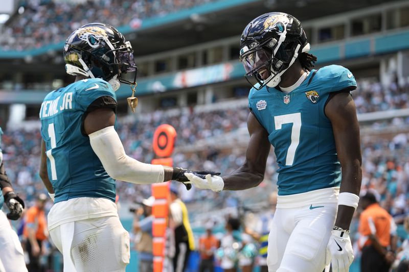 Jacksonville Jaguars wide receiver Brian Thomas Jr. (7) celebrates after scoring a touchdown with running back Travis Etienne Jr. (1) during the first half of an NFL football game against the Miami Dolphins, Sunday, Sept. 8, 2024, in Miami Gardens, Fla. Etienne Jr. scored a touchdown earlier in the game. (AP Photo/Rebecca Blackwell)