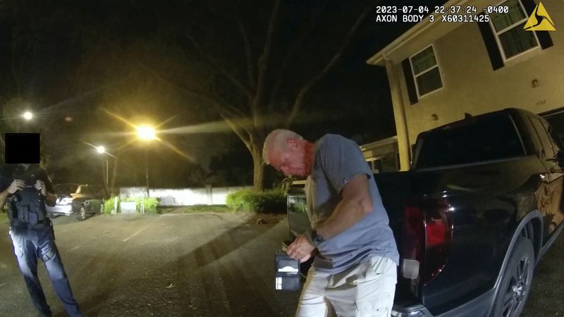 FILE - In this image from video provided by the Tampa Police Department, officers talk with Joseph Ruddy, a prosecutor with the U.S. Attorney's Office in Tampa, outside his home in Temple Terrace, Fla., on the evening of July 4, 2023. (Officer Taylor Grant/Tampa Police Department, File)