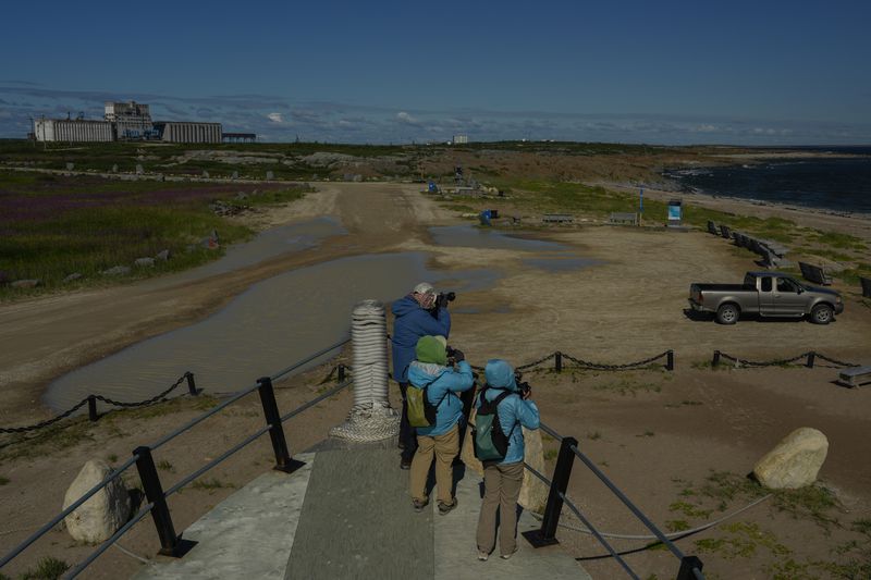 Tourists take photos of Hudson Bay while standing on an old whaling boat, Saturday, Aug. 3, 2024, in Churchill, Manitoba. (AP Photo/Joshua A. Bickel)