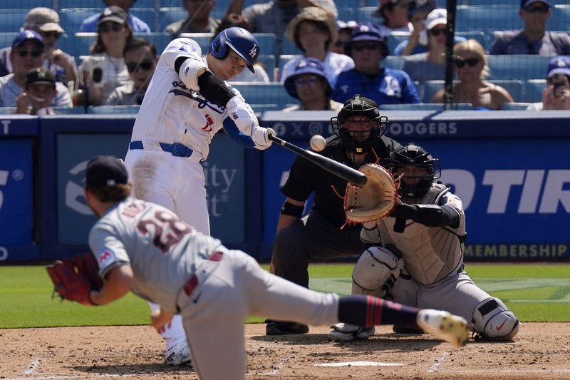 Los Angeles Dodgers' Shohei Ohtani, second from left, hits a solo home run as Cleveland Guardians starting pitcher Tanner Bibee, left, watches along with catcher Bo Naylor, right, and home plate umpire Dan Bellino during the fifth inning of a baseball game, Sunday, Sept. 8, 2024, in Los Angeles. (AP Photo/Mark J. Terrill)