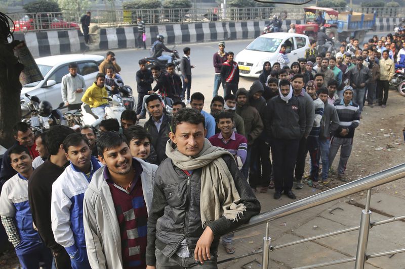 FILE- Indians wait outside a bank to withdraw money after the demonetization of currency, yanking 80% of bank notes from circulation in an effort to curb tax evasion, on the outskirts of New Delhi, India, Thursday, Dec. 8, 2016. Since coming to power a decade ago, Prime Minister Narendra Modi has been notorious for big, bold and often snap decisions, like demonetization, that he’s found easy to execute thanks to the brute majority he enjoyed in India's parliament. (AP Photo/Altaf Qadri, FILE)