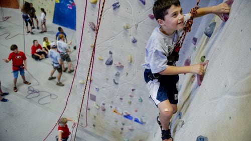 Aiden Levy (right) makes his way up a rock wall during climbing camp at the Stone Summit Climbing Center in Atlanta. JONATHAN PHILLIPS / SPECIAL