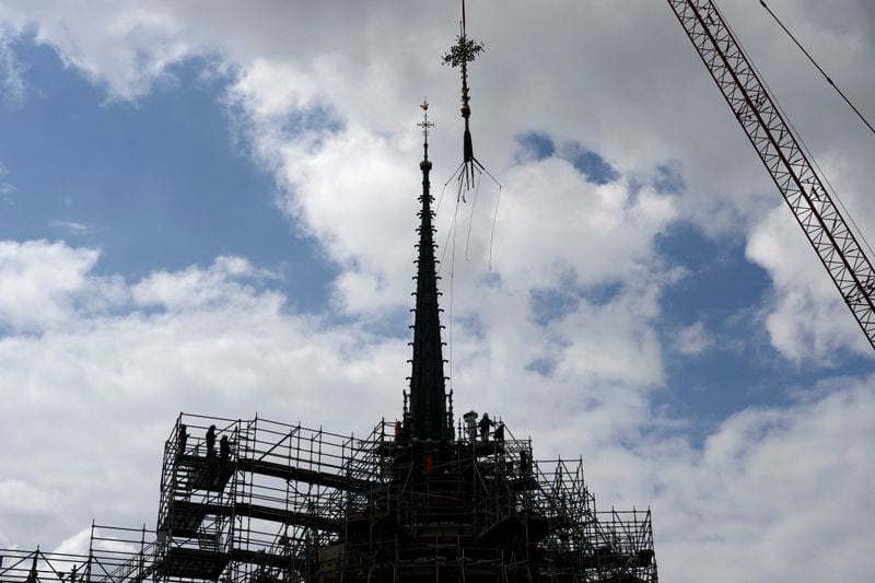 Notre Dame de Paris cathedral's Croix du Chevet is lifted to be reinstalled, Friday, May 24, 2024, in Paris. The Croix du Chevet is the only piece of the cathedral roof that did not burn in the devastating April 2019 fire. (AP Photo/Thibault Camus)