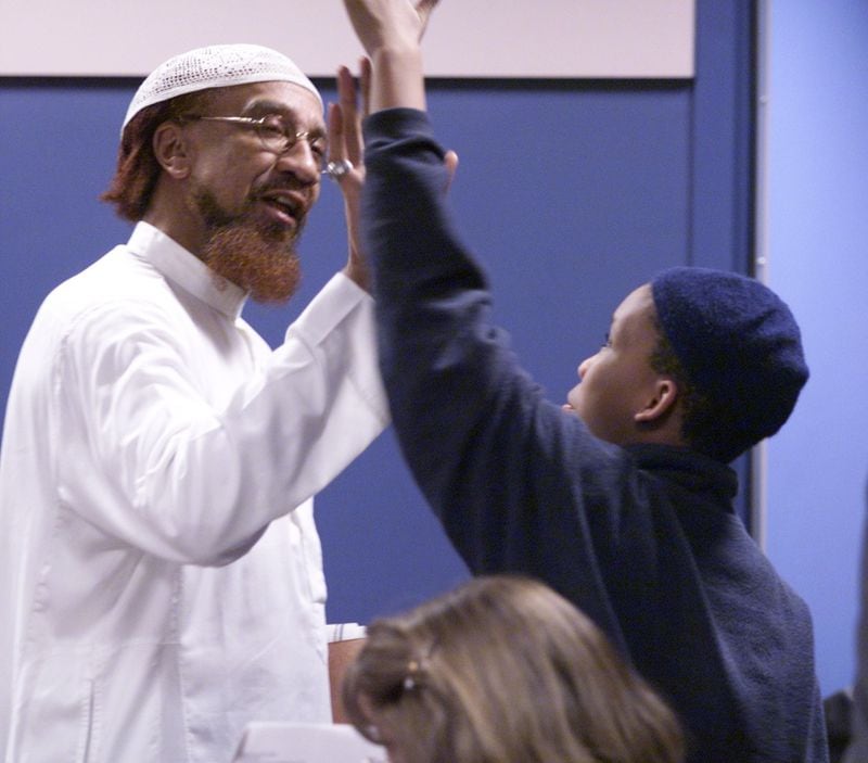 Jamil Abdullah Al-Amin spends a moment with his son Kairi while his lawyers pack up after jury selection for his murder trial in Fulton County Superior Court on Feb. 18, 2002. (PHIL SKINNER /AJC file photo)