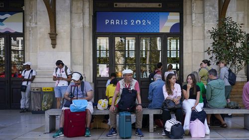 Travelers wait outside the Gare de Bordeaux Saint-Jean at the 2024 Summer Olympics, Friday, July 26, 2024, in Bordeaux, France. Hours away from the grand opening ceremony of the Olympics, high-speed rail traffic was severely disrupted. (AP Photo/Moises Castillo)
