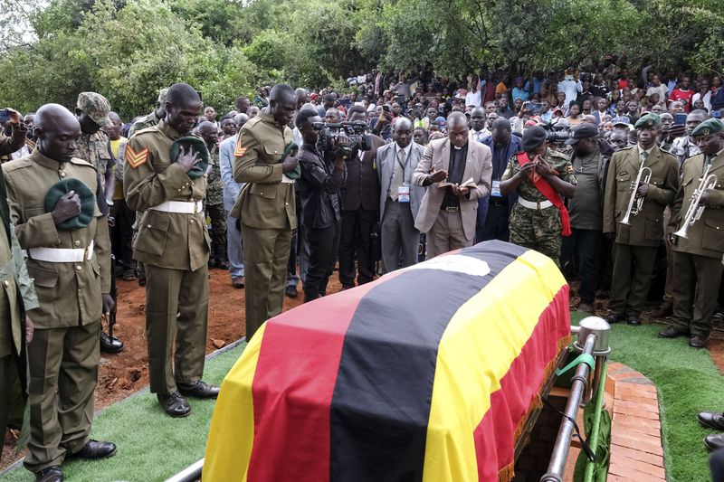 Members of the Uganda People's Defense Force pay their respects at the funeral of Ugandan Olympic athlete Rebecca Cheptegei as her casket is lowered into the grave in Kapkoros, Bukwo District, Uganda, on Saturday, Sept. 14. 2024. (AP Photo/Hajarah Nalwadda)