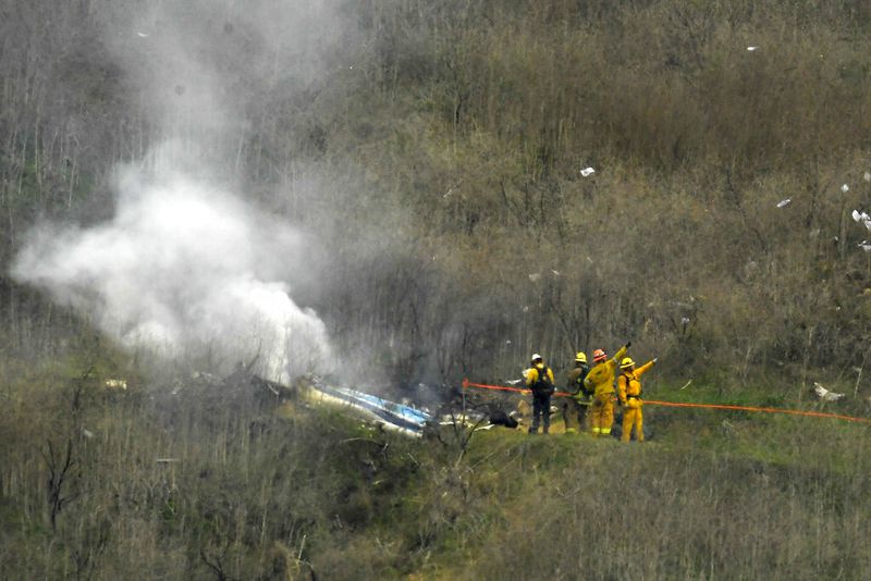 FILE - In this Jan. 26, 2020, file photo, firefighters work the scene of a helicopter crash where former NBA star Kobe Bryant died in Calabasas, Calif. Federal investigators said Wednesday, June 17, 2020, that the pilot of the helicopter that crashed in thick fog, killing Kobe Bryant and seven other passengers, reported he was climbing when he actually was descending.  (AP Photo/Mark J. Terrill, File)