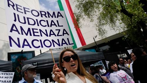 A demonstrator holds the sign "Judicial reform national threat" during a protest outside the Senate against a judicial reform bill in Mexico City, Thursday, Sept. 5, 2024, the day after Congress passed legislation that would require all judges to stand for election. (AP Photo/Felix Marquez)