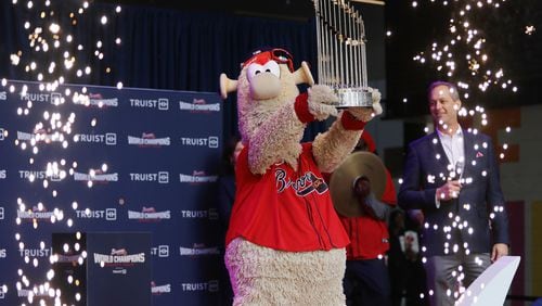 Braves mascot Blooper shows the 2021 World Champions trophy to the public during the first stop of the World Champions Trophy Tour on Feb. 15 at Colony Square in Midtown. Braves President and CEO Derek Schiller looks on. (Miguel Martinez for The Atlanta Journal-Constitution)