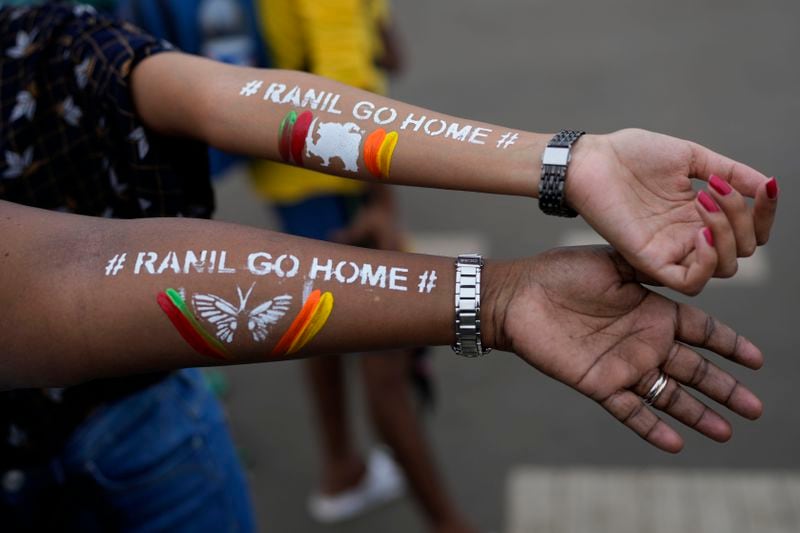 Girls display their arms painted with messages "Ranil Go Home' referring to Sri Lanka's Prime Minister Ranil Wickremesinghe at a protest site in Colombo, Sri Lanka, Sunday, July 17, 2022. (AP Photo/Rafiq Maqbool, File)