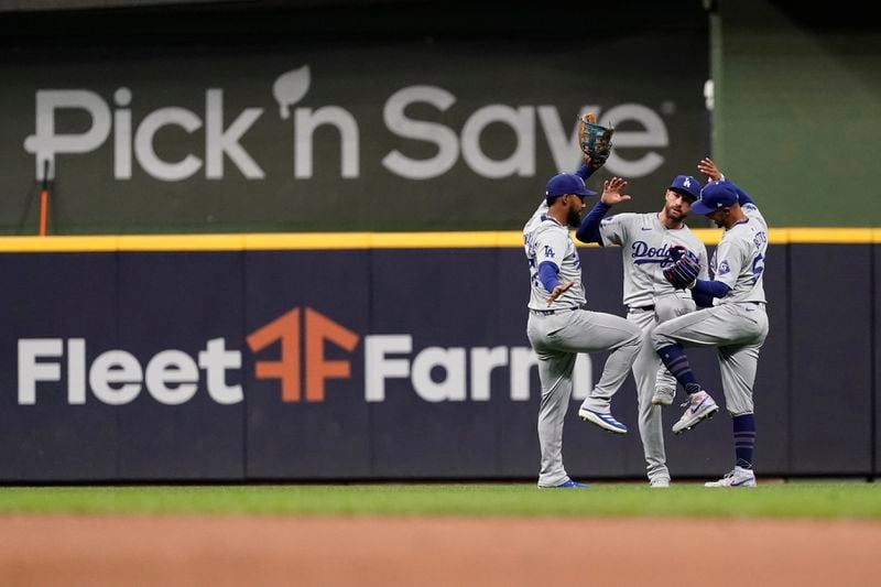 Los Angeles Dodgers' Kevin Kiermaier, center, Teoscar Hernández, left, and Mookie Betts, right, celebrate after a baseball game against the Milwaukee Brewers, Monday, Aug. 12, 2024, in Milwaukee. (AP Photo/Aaron Gash)