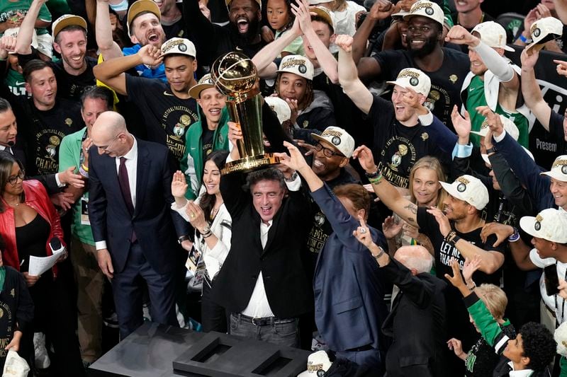Boston Celtics owner Wyc Grousbeck raises the trophy after defeating the Dallas Mavericks in Game 5 of the NBA basketball finals, Monday, June 17, 2024, in Boston. (AP Photo/Michael Dwyer)