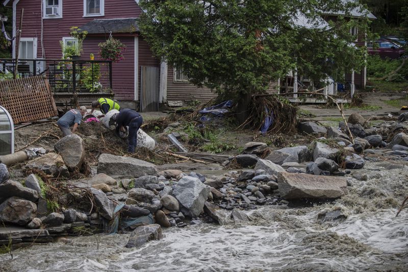Residents collect debris following flooding caused by the remnants of Hurricane Beryl, Thursday, July 11, 2024, in Plainfield, Vt. (AP Photo/Dmitry Belyakov)