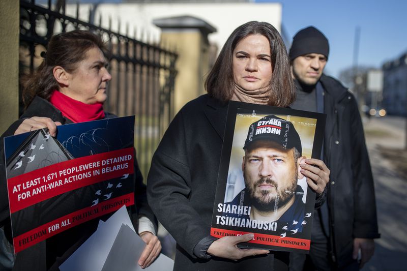 FILE - Belarusian opposition leader Sviatlana Tsikhanouskaya, center, holds a portrait of her jailed husband, Siarhei Tsikhanouski, at a protest outside the Belarus Embassy, in Vilnius, Lithuania, on March 8, 2024, demanding freedom for political prisoners. (AP Photo/Mindaugas Kulbis, File)