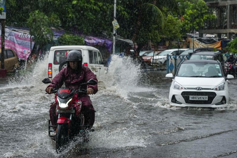 Vehicles move through a waterlogged street in Kolkata, India, as rain continues after cyclone Remal made a landfall near Bangladesh-India border, Monday, May 27, 2024. (AP Photo/Bikas Das)